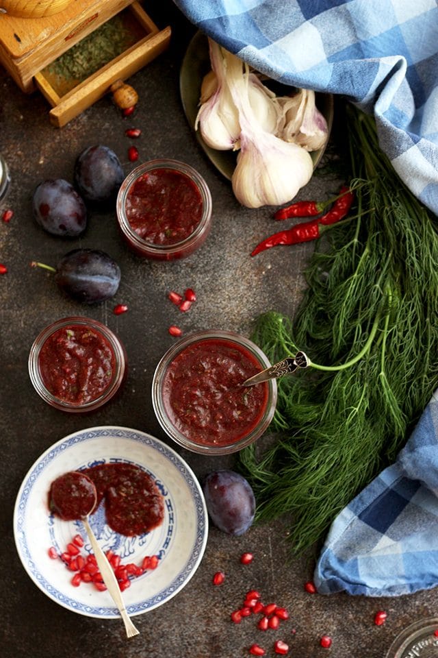 Georgian plum sauce on the tabletop surrounded by fresh dill and garlic.