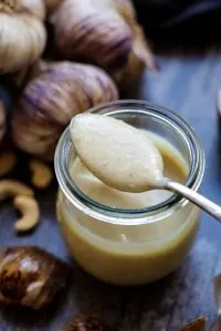 A jar of roasted garlic sauce with a spoon.