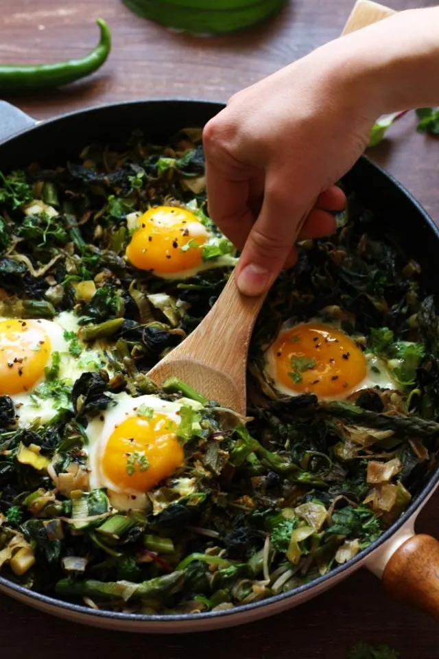 Green Shakshuka - Grabbing an Egg with a Wooden Spoon from the Pan