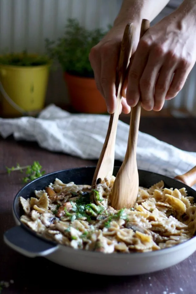 Rustic Creamy Mushroom Pasta with Hands in Action Ready to Serve
