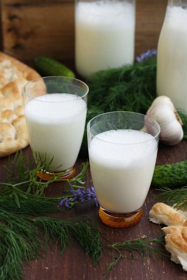 Ayran in glasses surrounded by dill and flatbread.