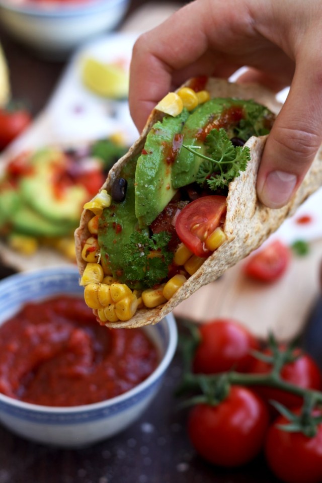 Hand holding a Vegan Taco with Avocado, Corn and Black Beans