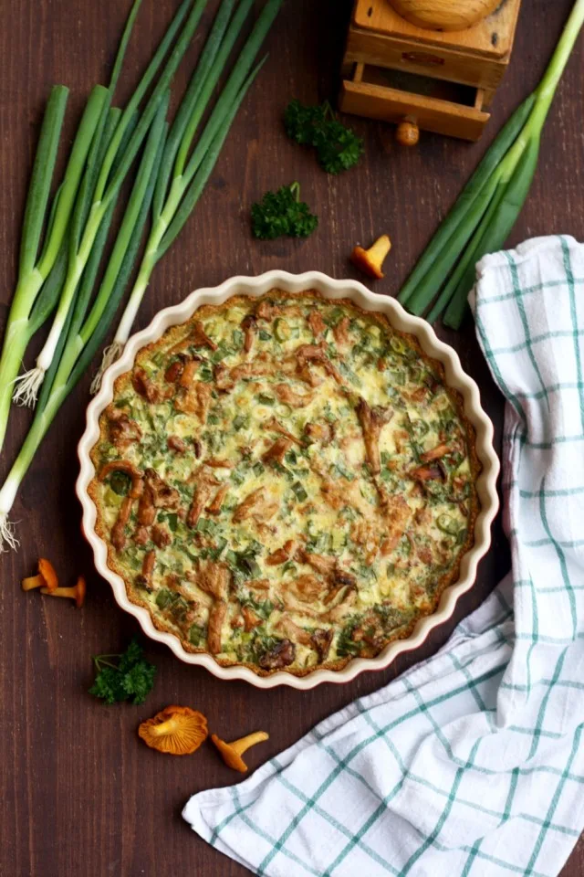 Mushroom quiche with quinoa pie crust in a baking dish with scallions