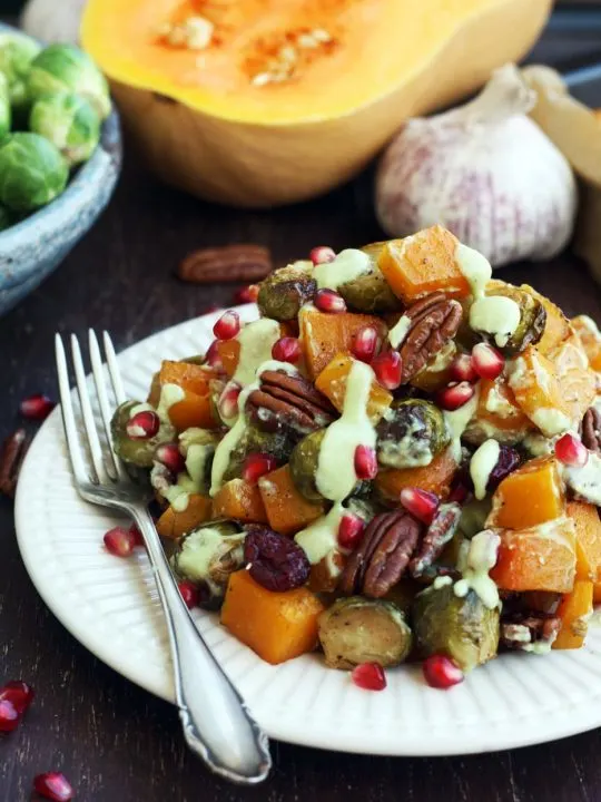Roasted Brussels Sprouts with Butternut Squash Served on a Plate with Pomegranate Seeds on the Table