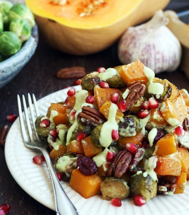 Roasted Brussels Sprouts with Butternut Squash Served on a Plate with Pomegranate Seeds on the Table