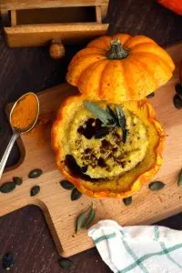 Easy Pumpkin Soup with Millet in Pumpkin Bowls - Served on the Wooden Board with a Spoon Full of Spice