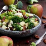 Healthy Broccoli Salad with Vegan Bacon, Apples, Blue Cheese and Pecans Pouring Dressing - in the Process of Pouring Sauce Over the Salad