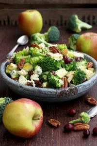 Healthy Broccoli Salad with Vegan Bacon, Apples, Blue Cheese and Pecans Pouring Dressing - Beautiful Composition Before the Dressing Being Poured Over