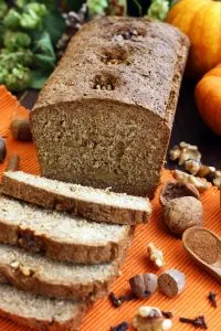 Healthy Pumpkin Bread with Walnuts - Cut into Pieces with Spices and Pumpkin in the Background