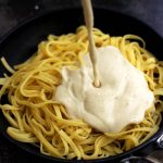 The Creamiest Vegan Fettuccine Alfredo - Vegan Fettuccine Alfredo Sauce Being Poured Over Pasta