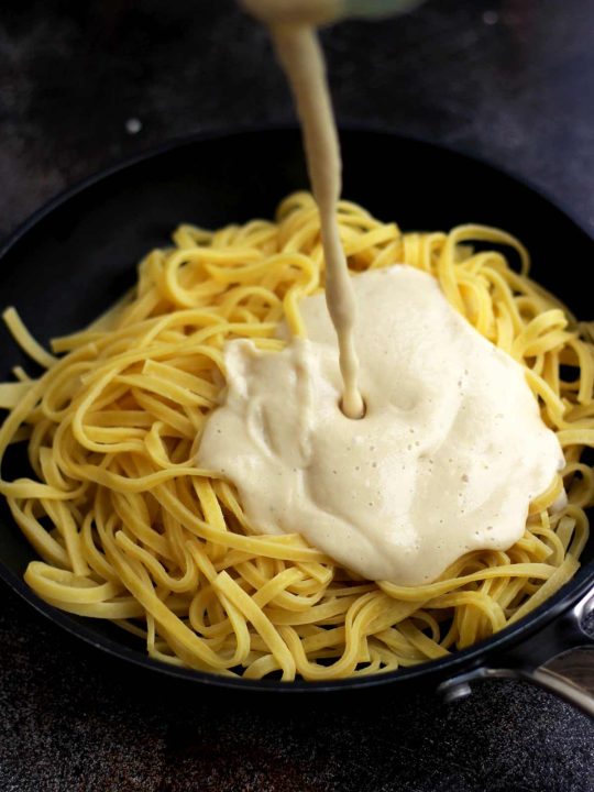 The Creamiest Vegan Fettuccine Alfredo - Vegan Fettuccine Alfredo Sauce Being Poured Over Pasta