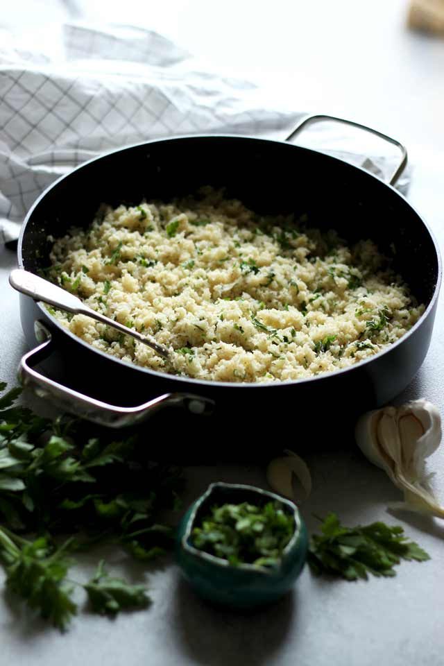 Rice in a Skillet with Garlic and Parsley Next to It