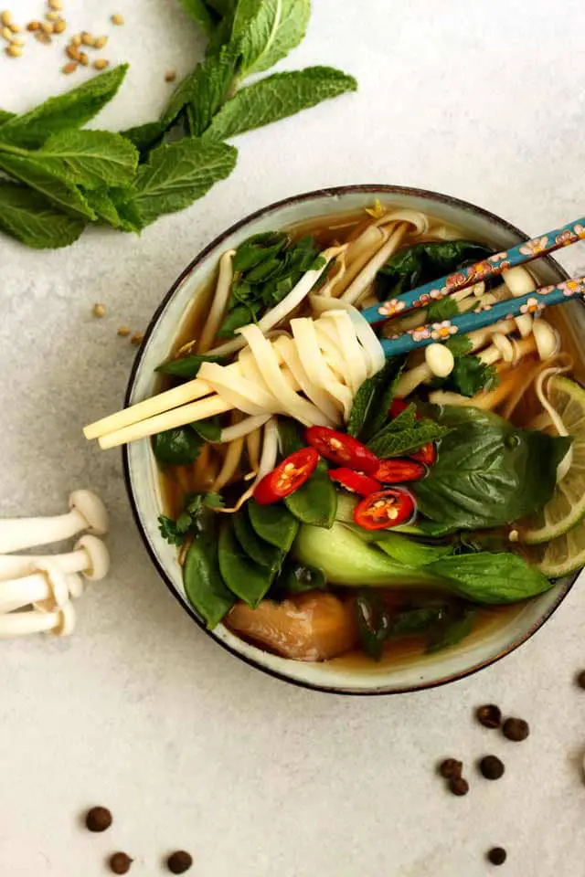 Vietnamese Vegan Pho in a Bowl Garnished with Chili Peppers and Herbs