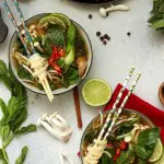 Easy Vegan Pho (Vietnamese Noodle Soup) Overhead with Two Bowls and Plenty of Ingredients on the Table