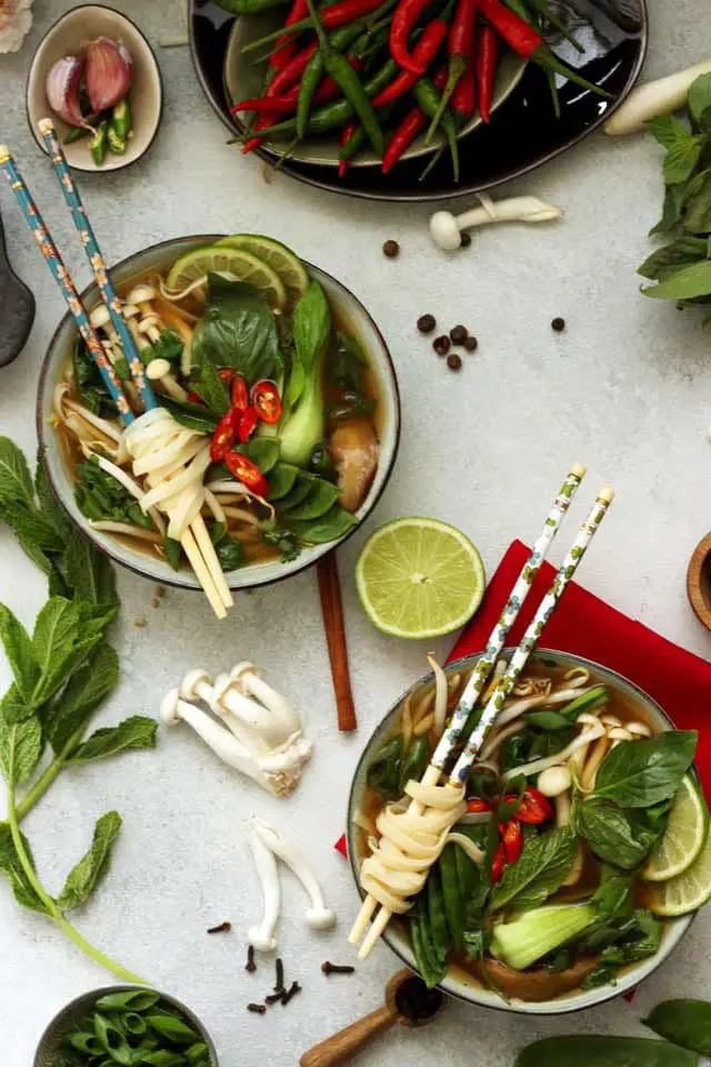 Easy Vegan Pho (Vietnamese Noodle Soup) Overhead with Two Bowls and Plenty of Ingredients on the Table