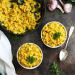 #ad Silky Vegan Mac and Cheese Overhead Shot on Two Bowls and a Pan with Garlic and Herbs Around