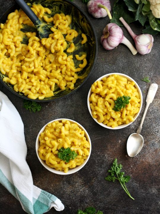 #ad Silky Vegan Mac and Cheese Overhead Shot on Two Bowls and a Pan with Garlic and Herbs Around