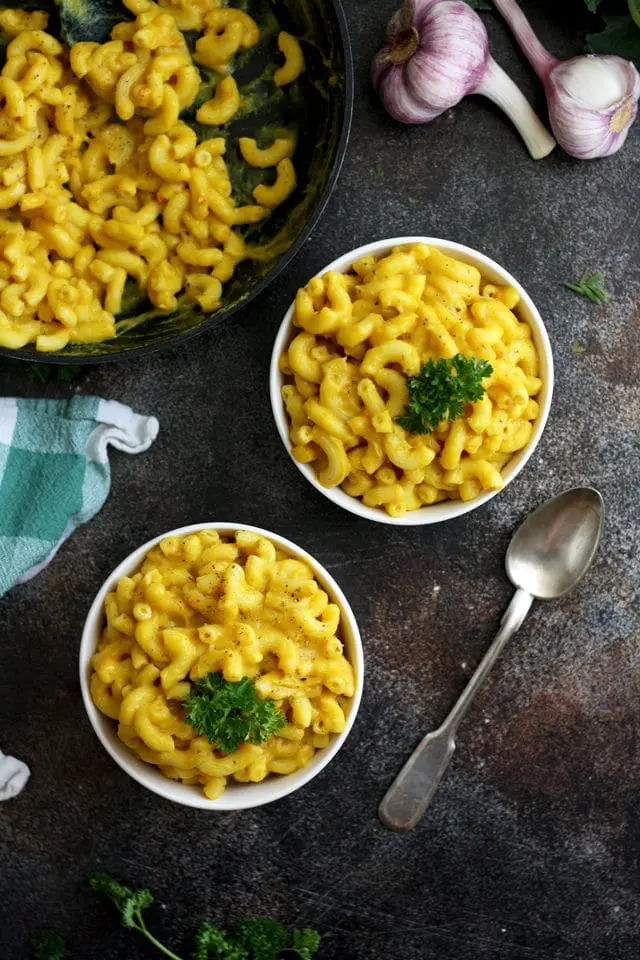 Silky Vegan Mac and Cheese Closeup Shot on Two Bowls and a Pan Full of the Delicious Dish