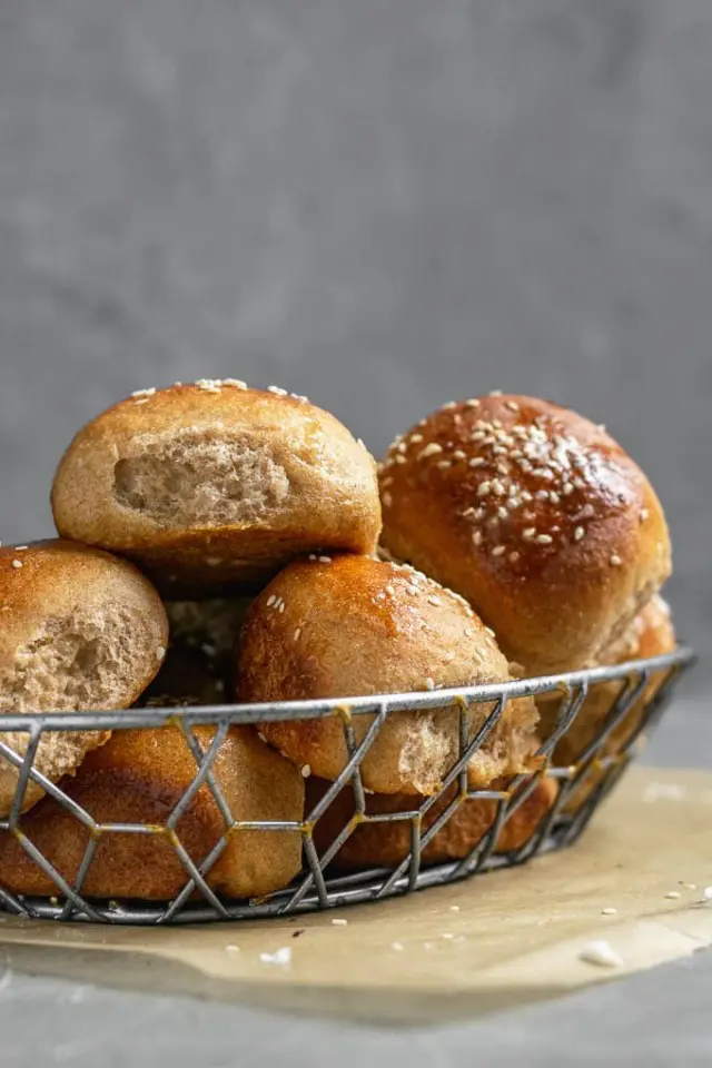 Soft whole wheat dinner rolls in a metal basket.