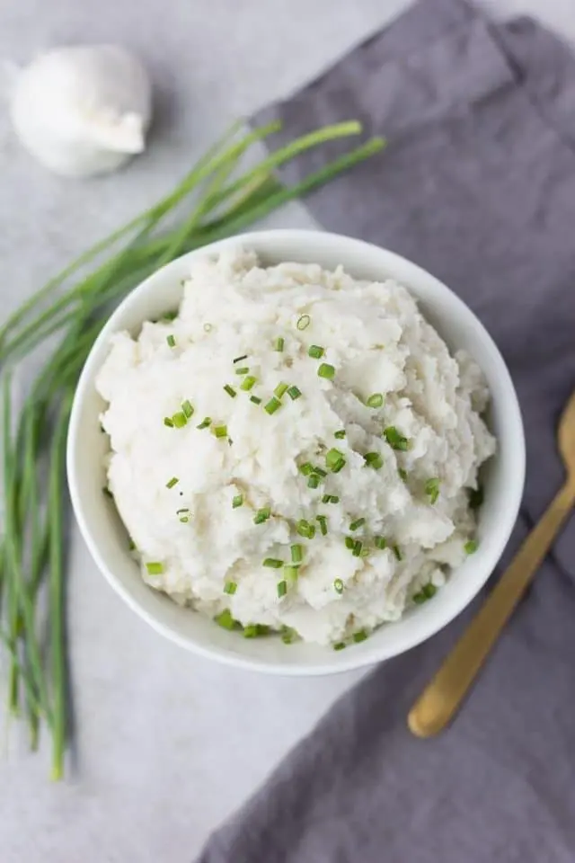 Vegan Mashed Potatoes in a white bowl garnished with chives.