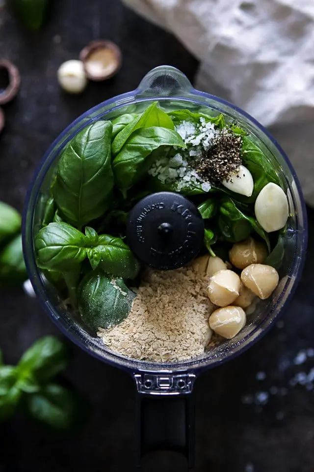 Ingredients for Pesto in the Chopper: Basil Leaves, Macadamia Nuts, Nutritional Yeast, Garlic Cloves, Olive Oil, Salt and Pepper