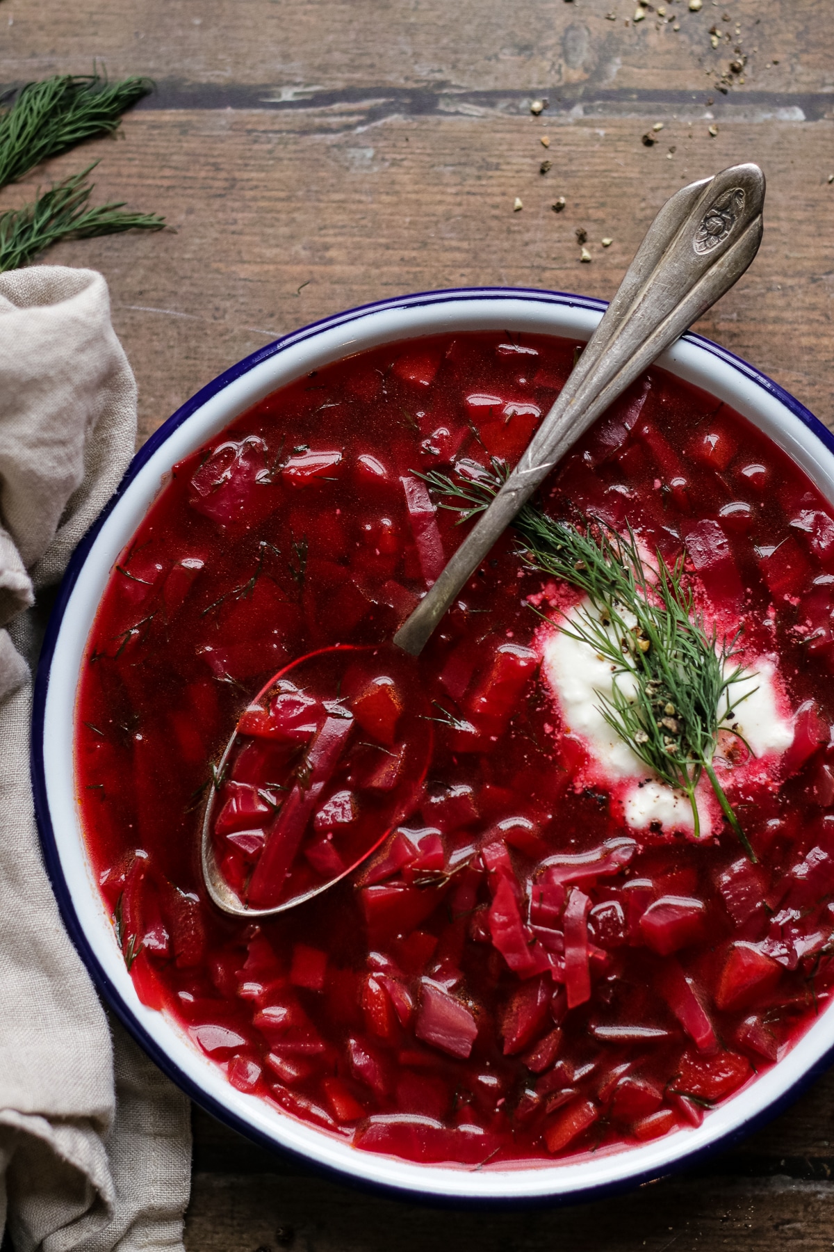 Closeup of a plate with borscht garnished with dill and sour cream.