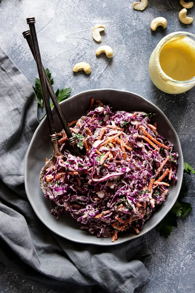 Coleslaw Salad on a Plate with Utensils Next to a Jar of Vegan Mayo