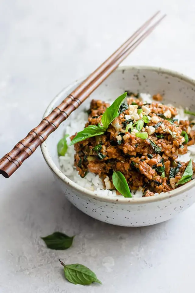 Thai basil tempeh stir fry ready and served in a bowl with two sticks on top