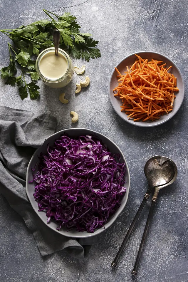 Shredded Purple Cabbage and Shredded Carrots Next to a Jar of Vegan Mayo and Parsley