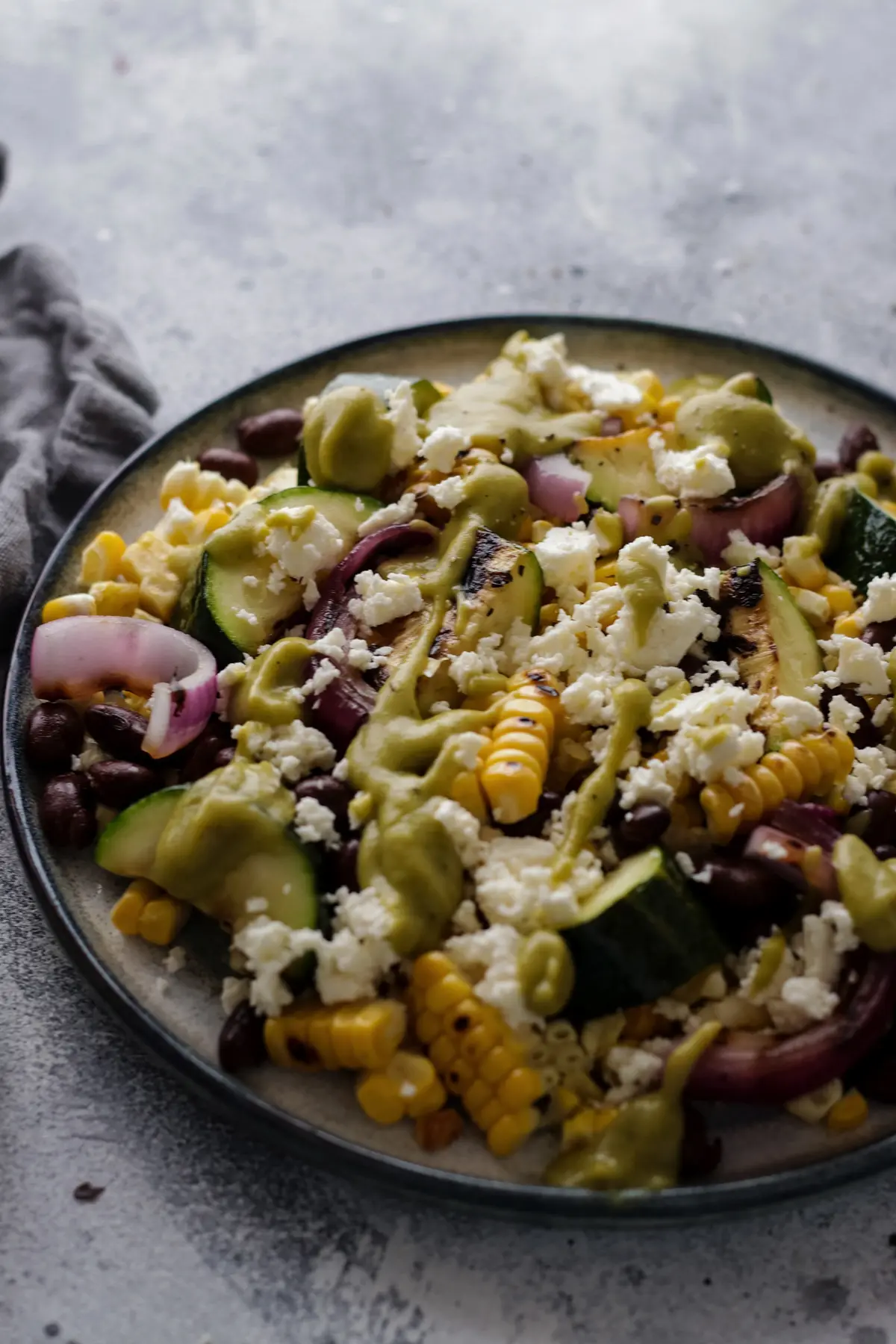 Grilled Zucchini and Corn Salad on a Grey Background.