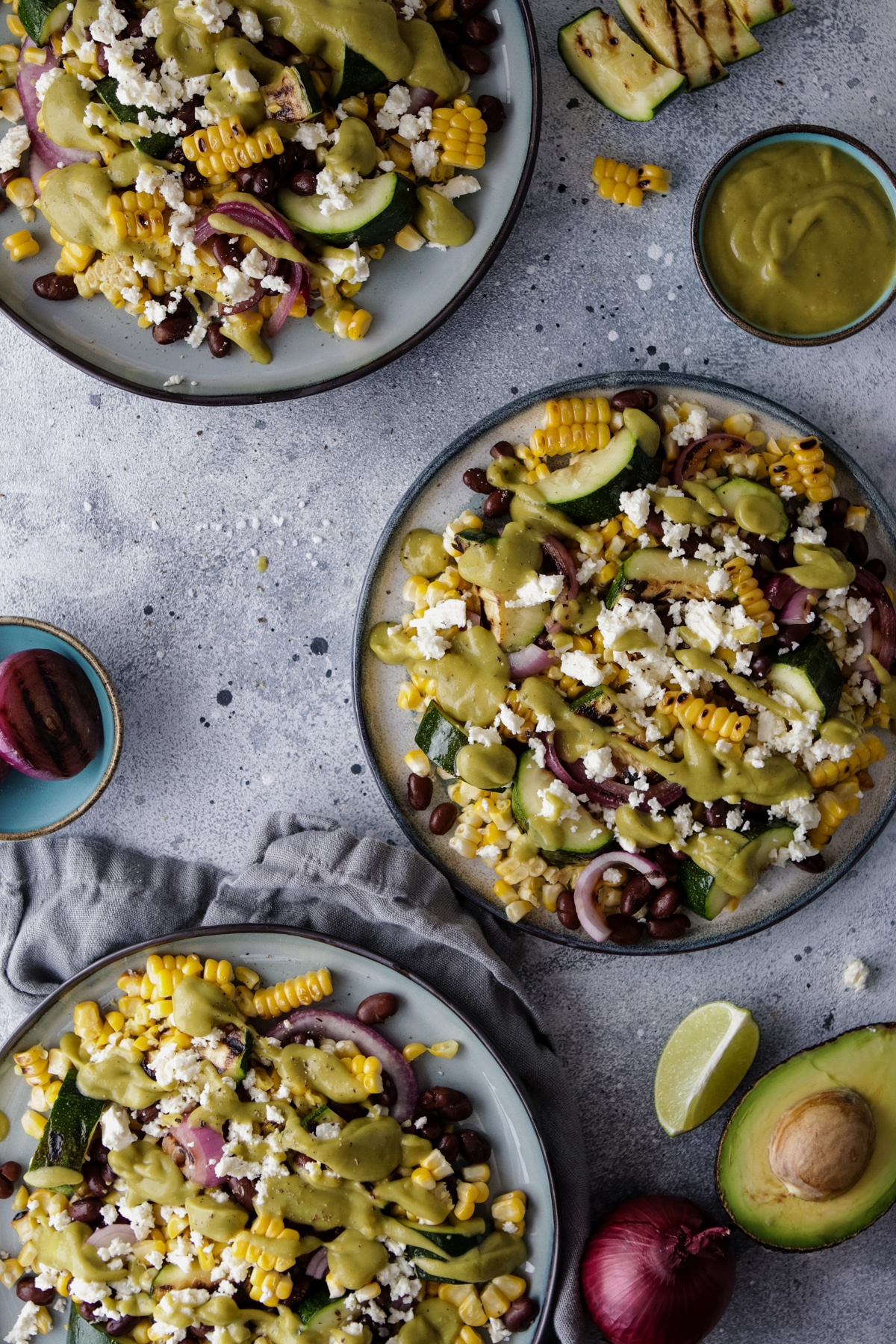Three Plates with Corn Zucchini Salad Surrounded by Ingredients