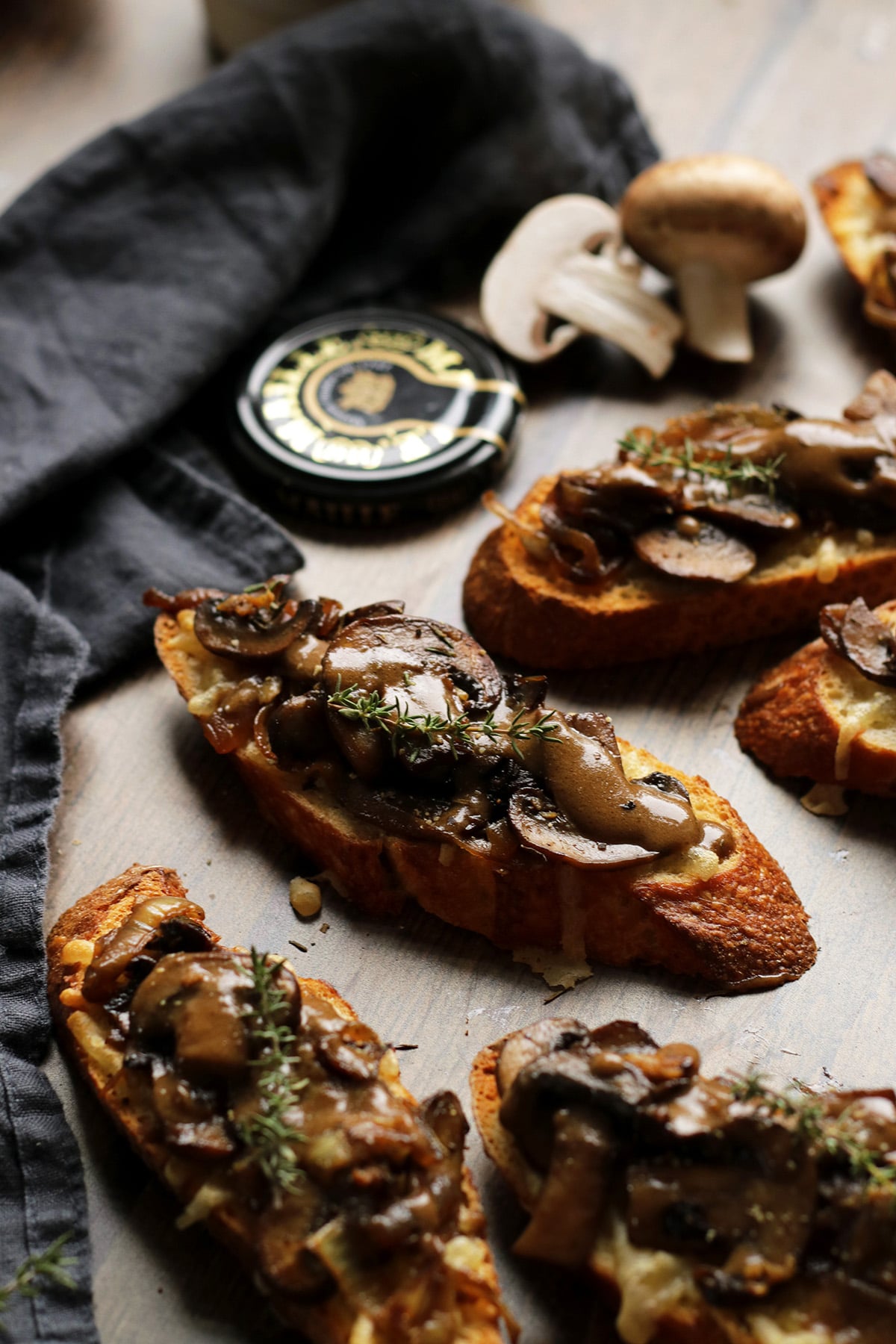 Vegan Crostini with Mushrooms and Caramelized Onions Next to a Mustard Lid.