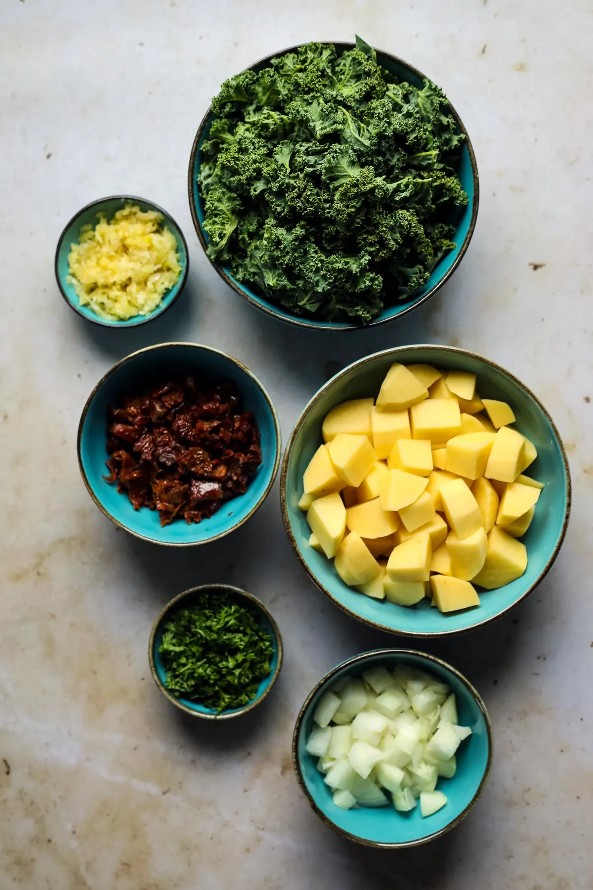 Prepped vegetables for kale potato soup in bowls.