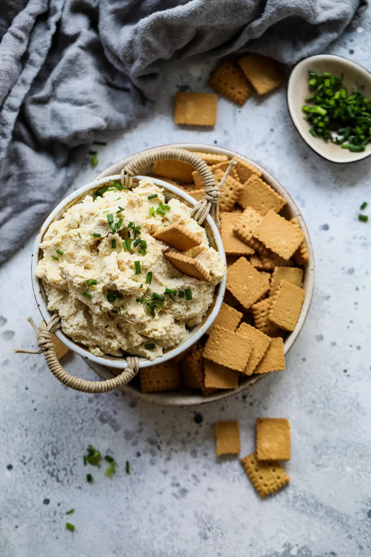 Dairy-free ricotta in a bowl with crackers and chives.