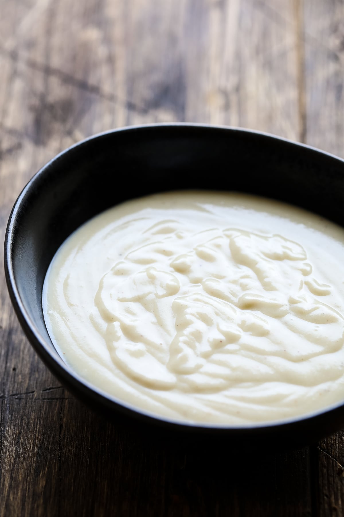 Creamy vegan bechamel in a dark bowl.