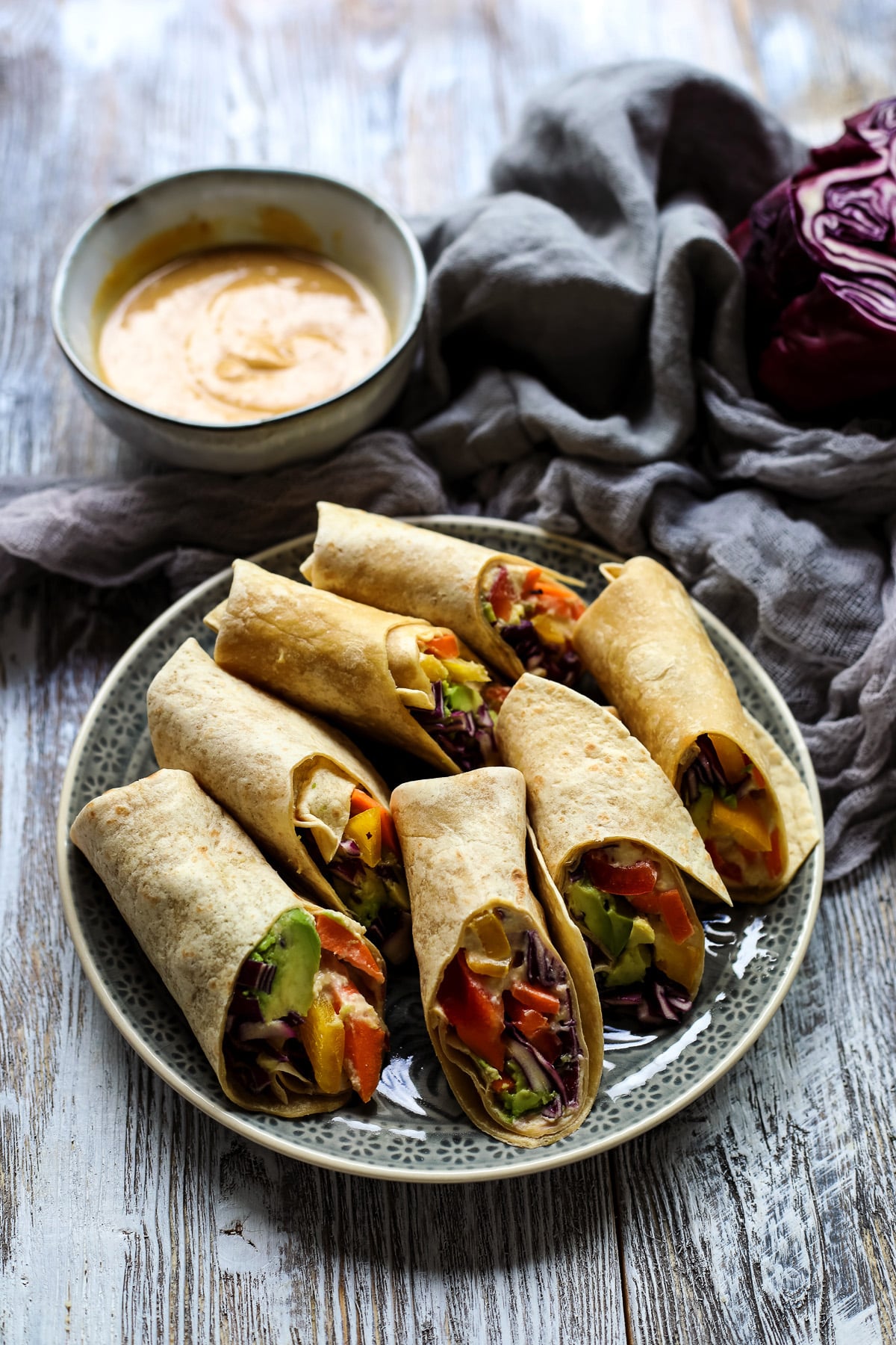 Rainbow wraps with hummus on a plate.