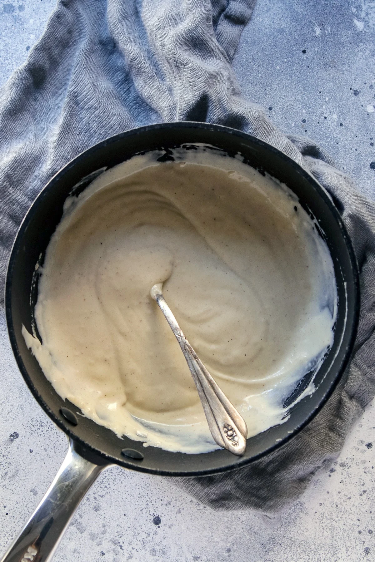 Vegan bechamel in a saucepan with a spoon.