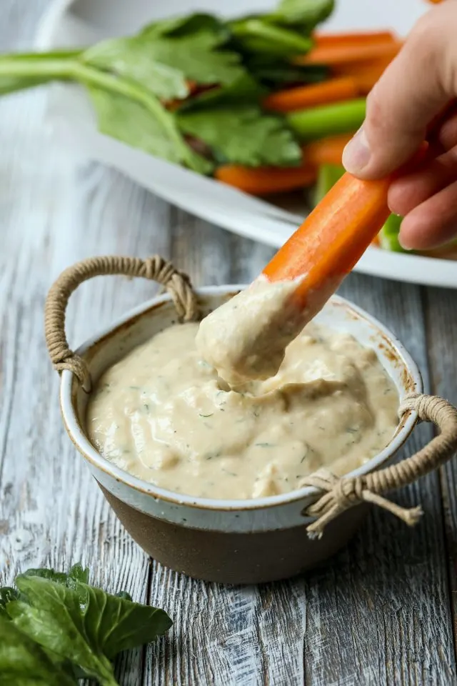 Dipping carrot stick into dairy-free blue cheese dip.
