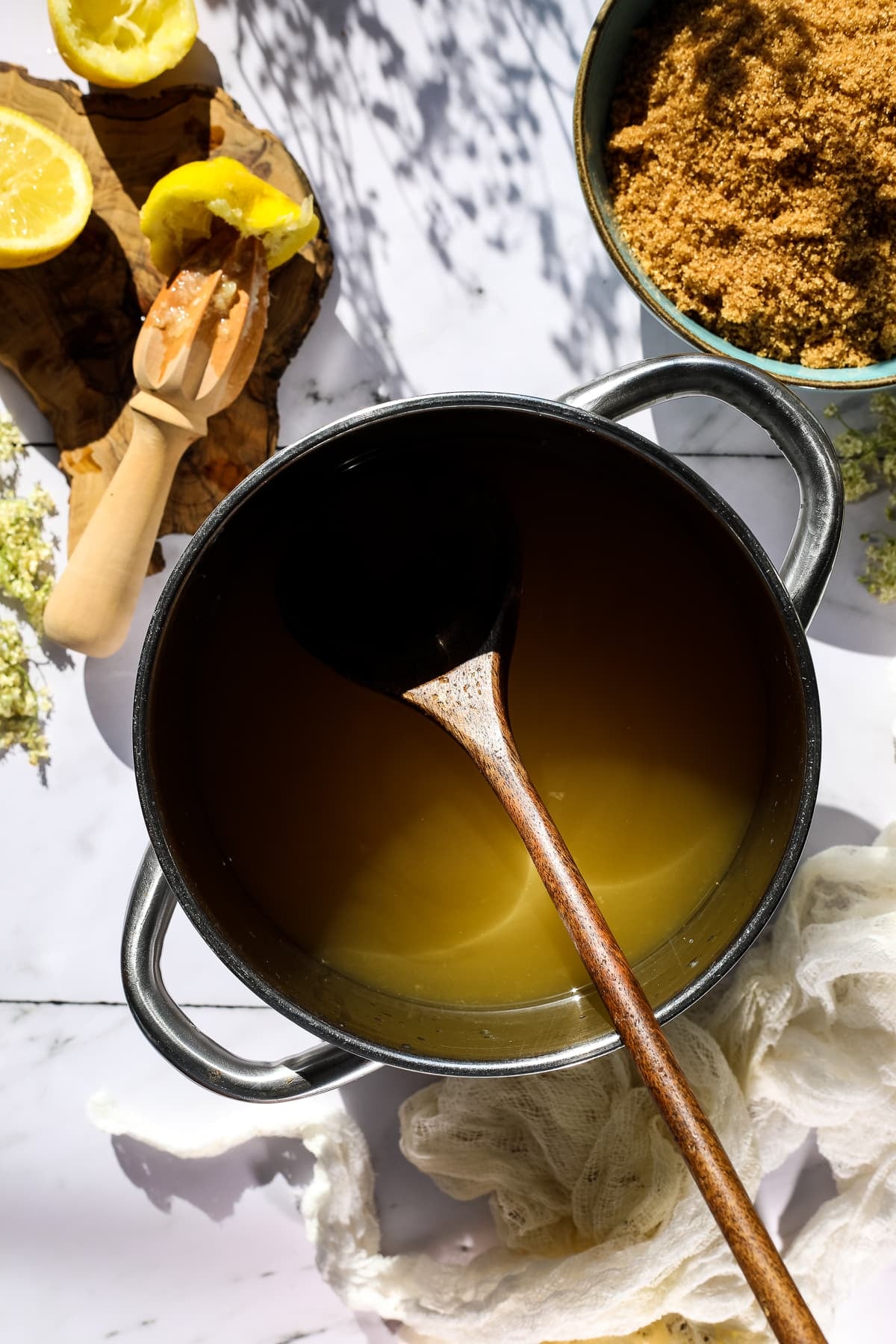 Homemade elderflower syrup in a pot with brown sugar.