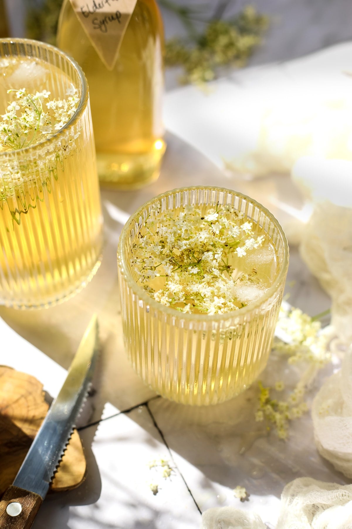 Elderflower syrup with water and flowers in a glass.