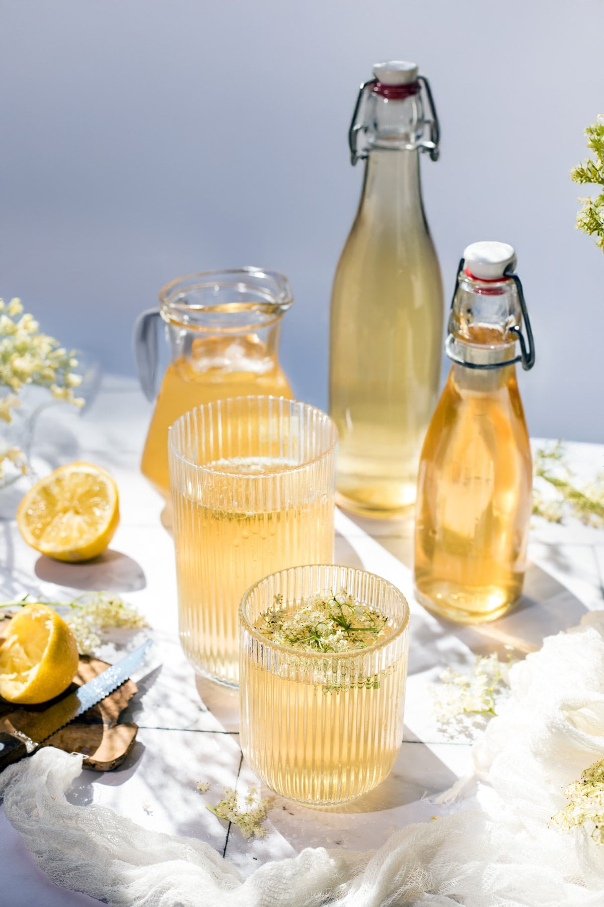 Glasses and bottles with elderflower syrup and lemonade.